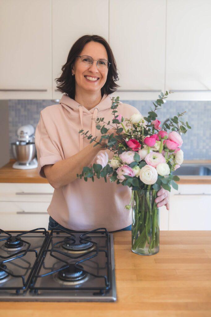 Hilfe beim Aufräumen Sandra Hoffmann steht in der Küche und ordnet Blumen in einer Vase