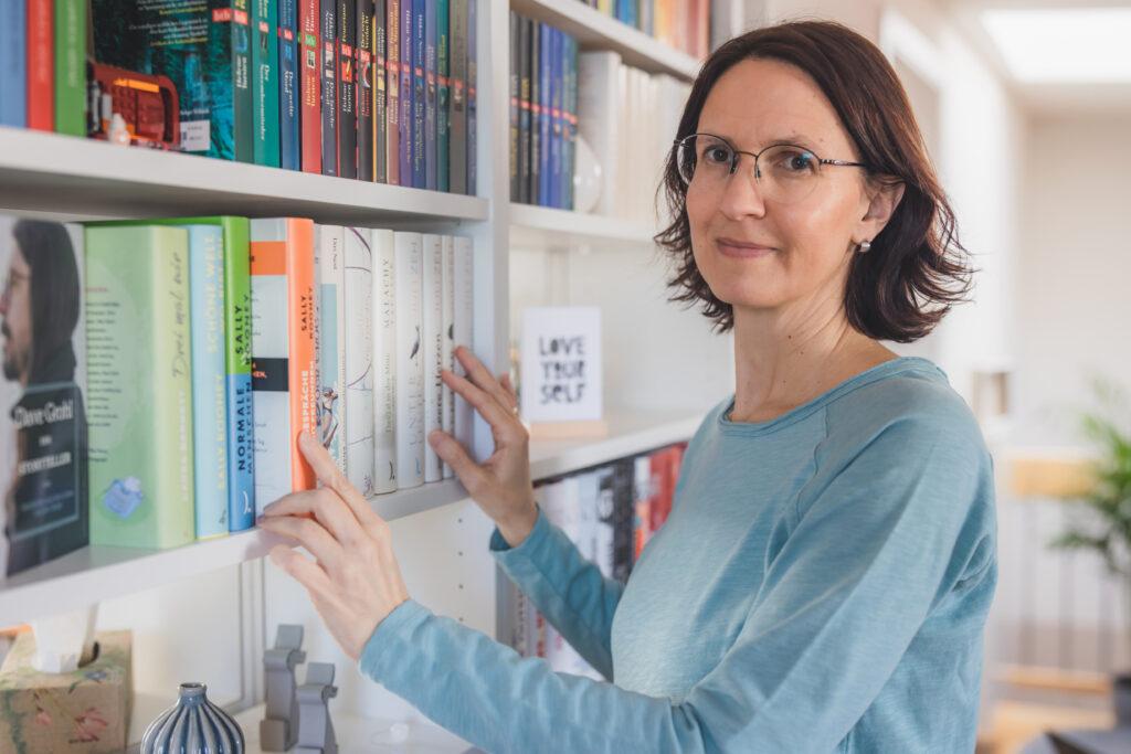 Ordnungscoach Sandra Hoffmann steht vor einem schön aufgeräumten Bücherregal